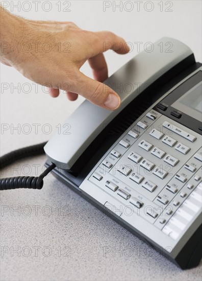 Man reaching for telephone receiver.