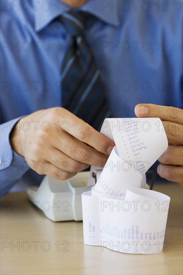 Businessman looking at adding machine tape.