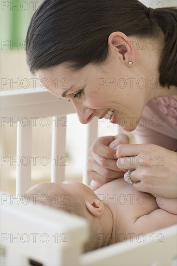 Mother smiling at baby in crib.