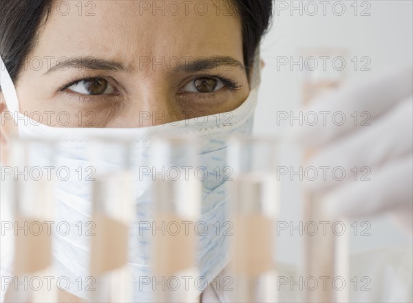 Female scientist looking at vials of liquid.