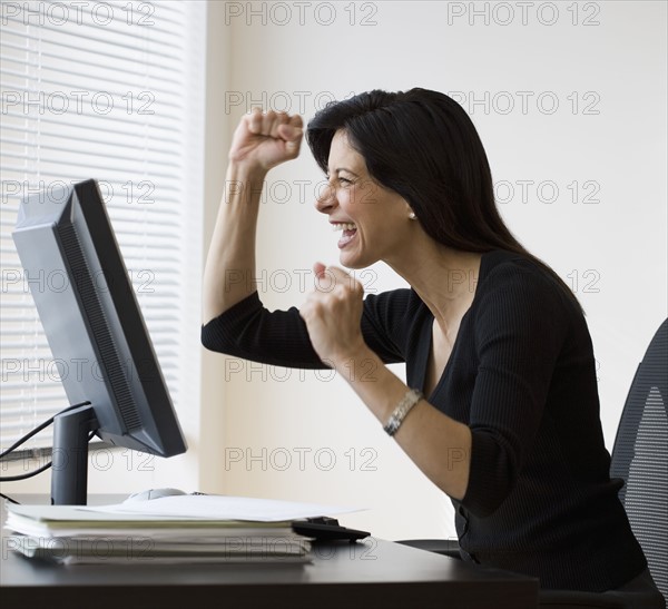 Businesswoman cheering at computer.