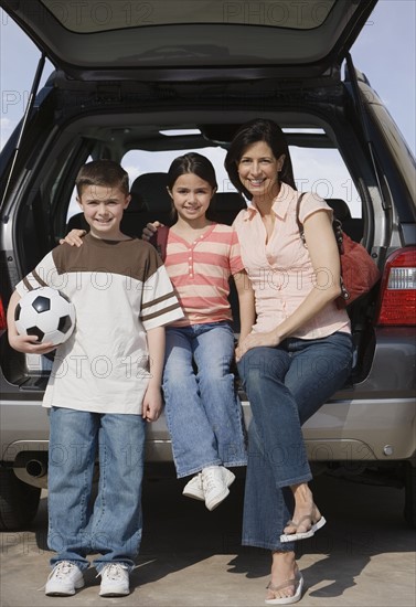 Mother and children on tailgate of truck.