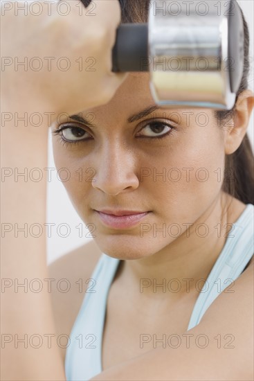 Indian woman holding dumbbell.