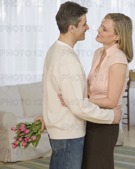 Couple hugging with flowers.