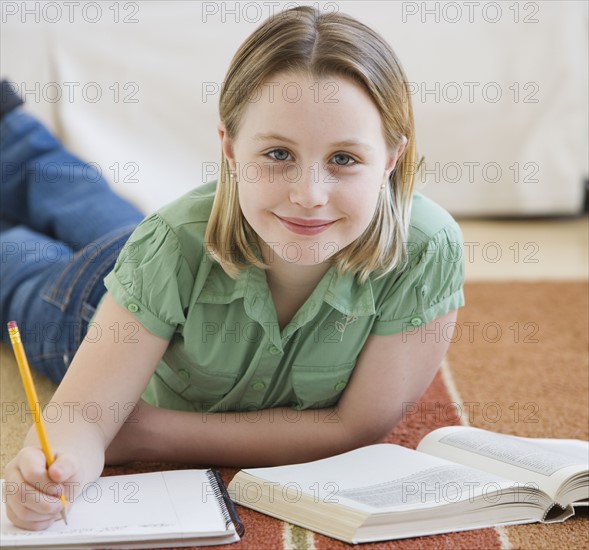 Girl doing homework on floor.