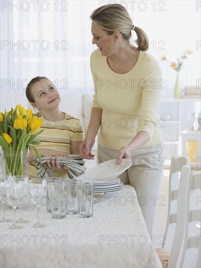 Mother and daughter setting table.