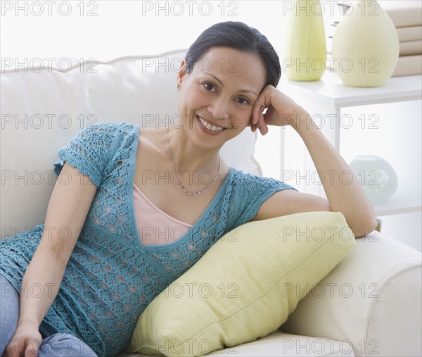 Asian woman sitting on sofa.