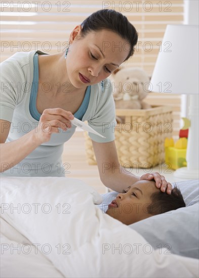 Asian mother taking son’s temperature.