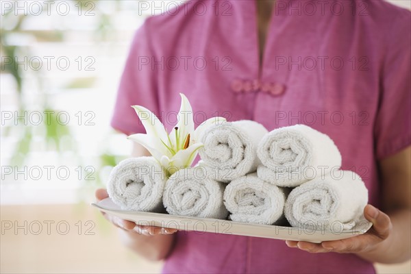 Woman holding tray of rolled towels.
