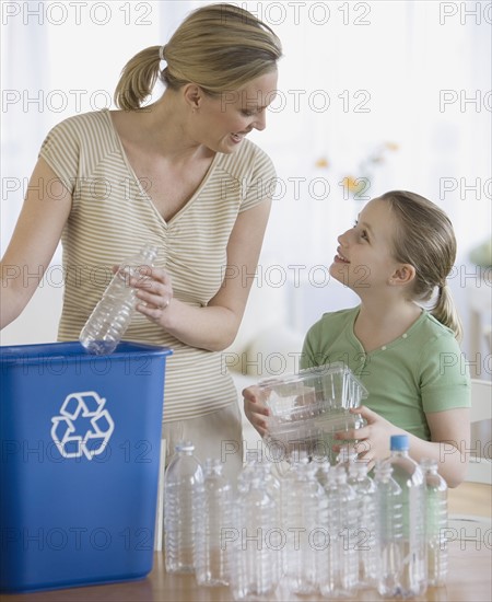 Mother and daughter filling recycle bin.