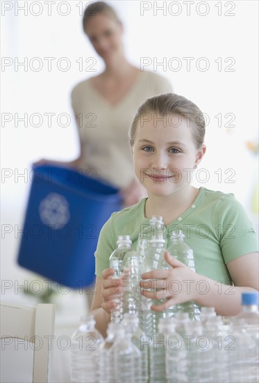 Mother and daughter filling recycle bin.