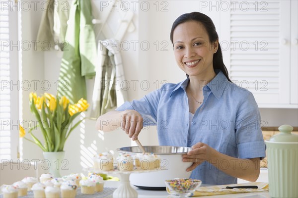 Asian woman stirring batter in kitchen.