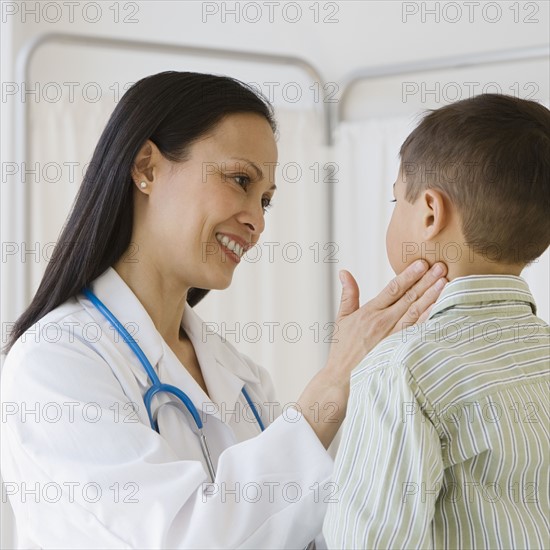 Asian female doctor examining boy’s glands.