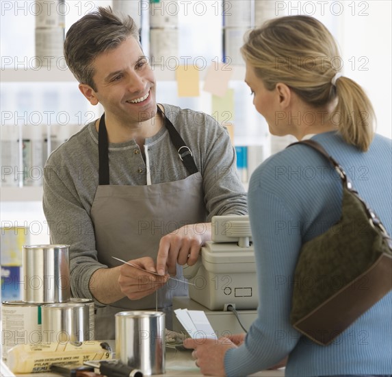 Woman talking to clerk at paint store.