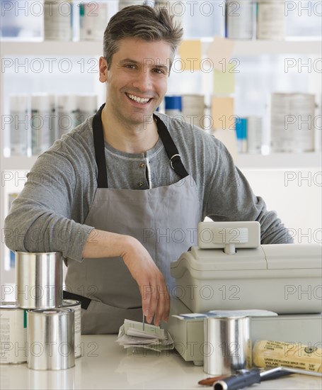 Male clerk at counter of paint store.