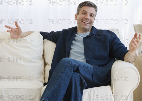 Man shrugging shoulders on sofa.