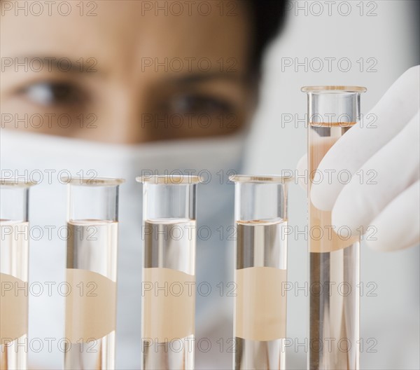 Female scientist looking at vials of liquid.