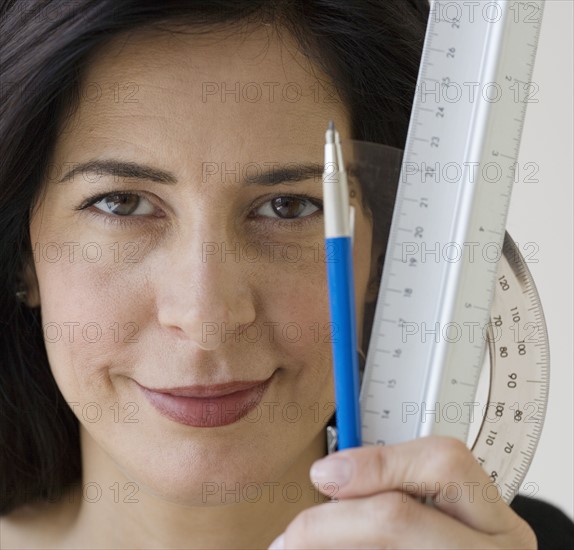 Woman holding ruler, protractor and pencil.