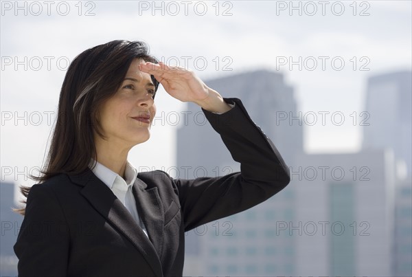 Businesswoman shielding eyes from sun.