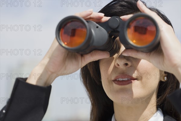 Businesswoman looking through binoculars.