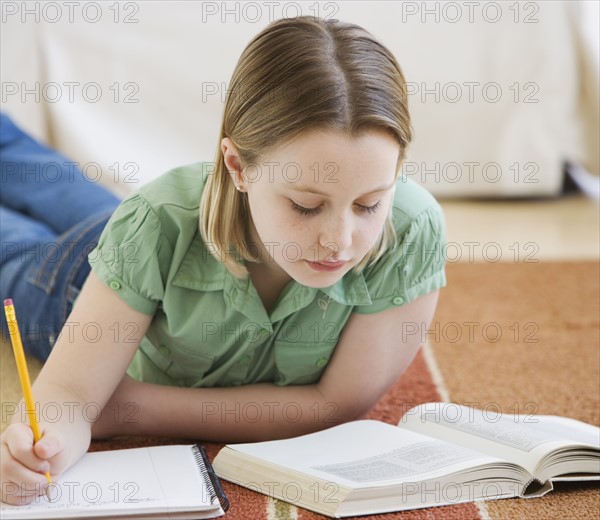 Girl doing homework on floor.