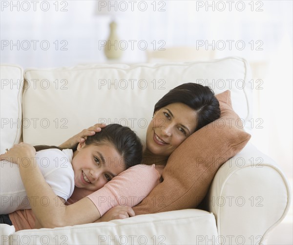 Mother and daughter hugging on sofa.