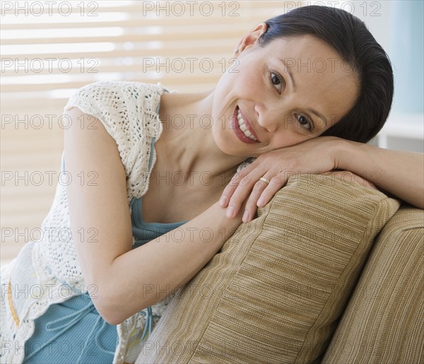 Asian woman sitting on sofa.