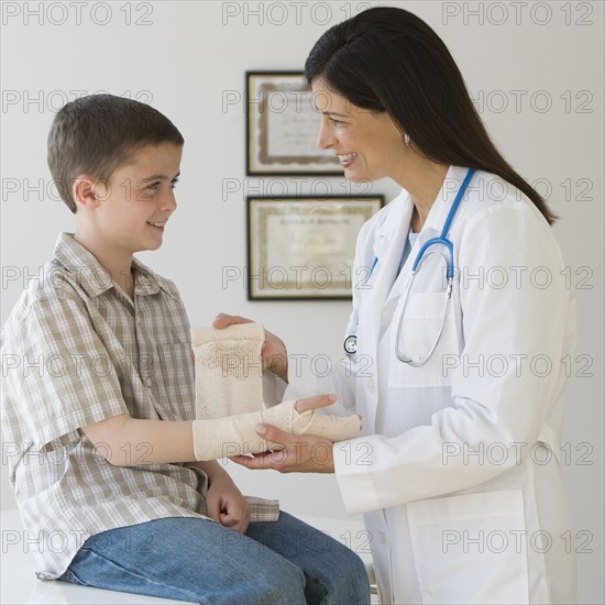 Female doctor wrapping boy’s wrist.