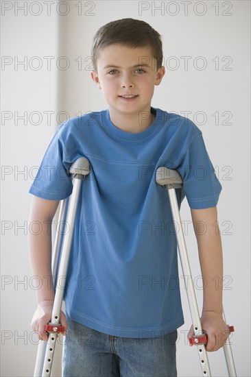 Boy standing on crutches.