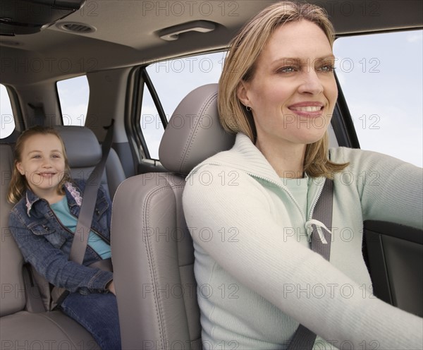 Mother driving car with daughter in back.