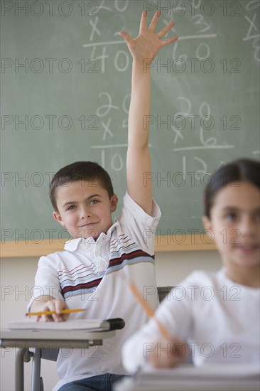 Boy raising hand in classroom.