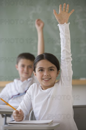 Girl raising hand in classroom.