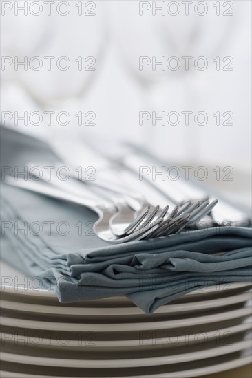 Stack of plates, silverware and napkins.