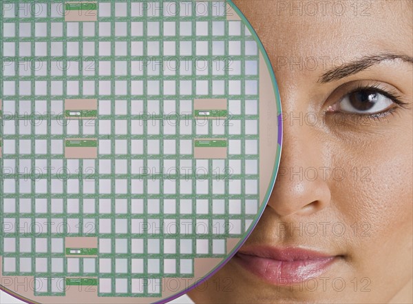 Indian woman holding disc in front of eye.