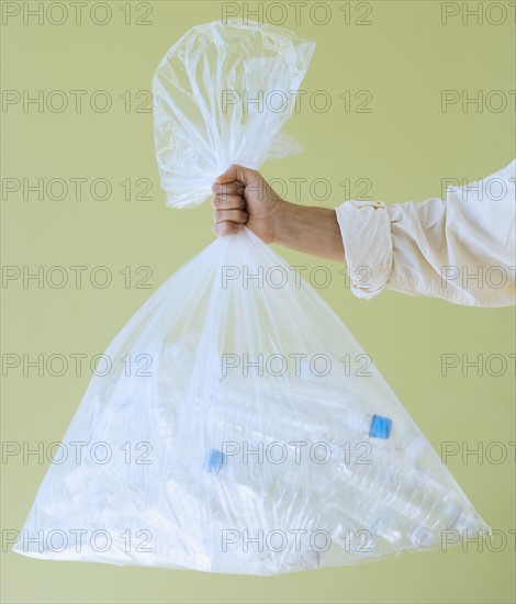 Hand holding bag of empty water bottles.