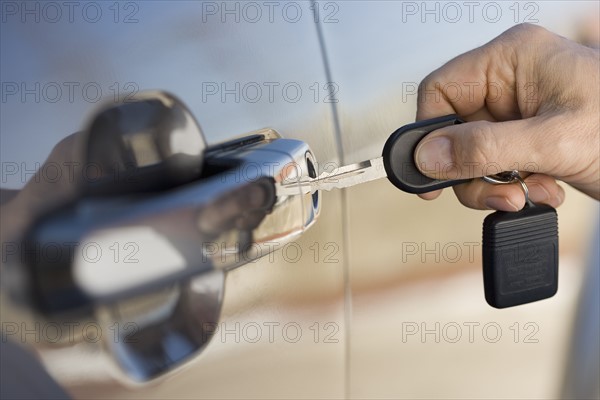 Man putting car key in door.