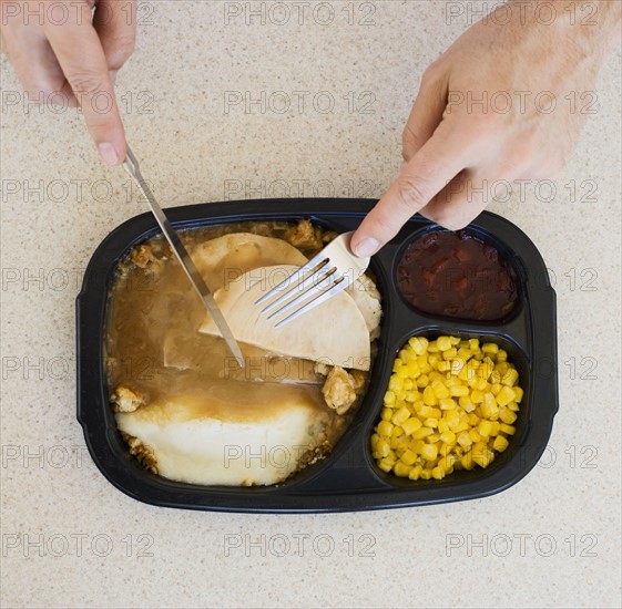 Close up of man eating TV dinner.