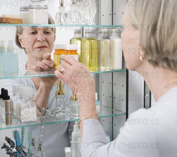 Senior woman looking in medicine cabinet.
