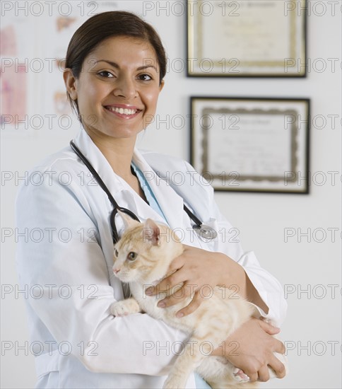 Indian female veterinarian holding cat.