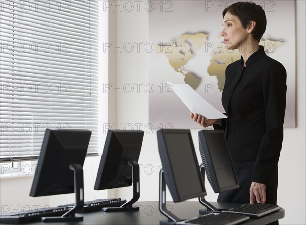 Businesswoman next to table with computers.