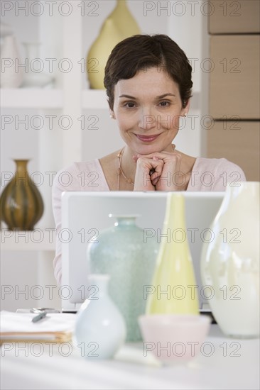 Woman with laptop in pottery store.