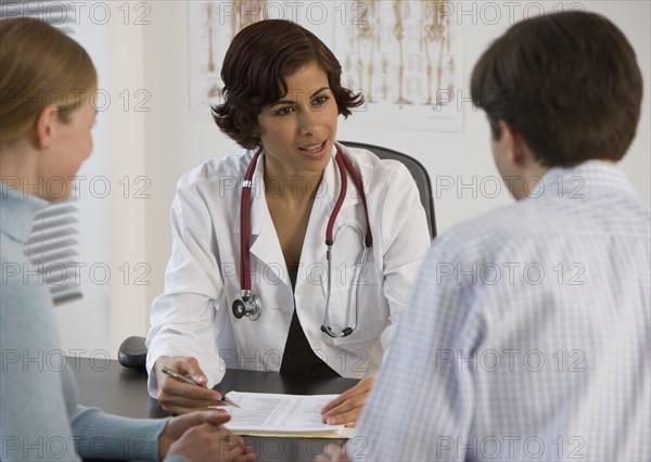 Female doctor talking to couple in office.