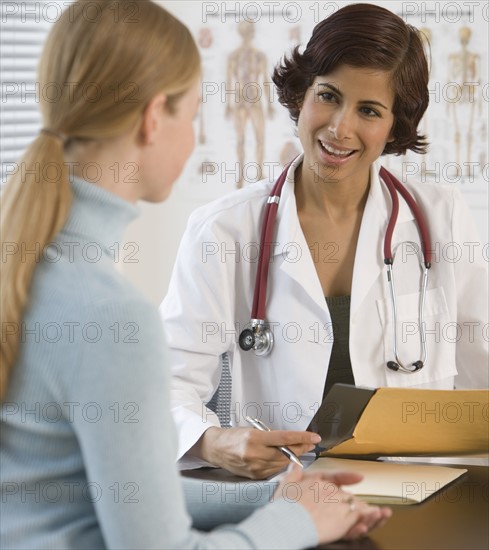 Female doctor talking to woman in office.