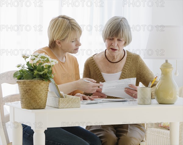 Mother and adult daughter looking at bills.