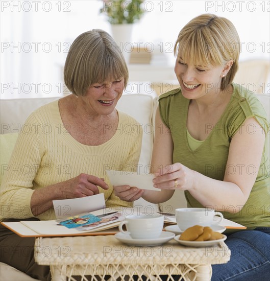 Mother and adult daughter looking at photographs.