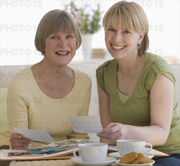 Mother and adult daughter looking at photographs.
