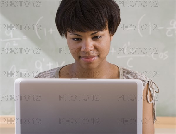 African woman using laptop in classroom.