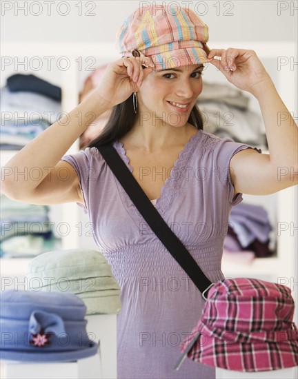 Woman tying on hat in store.