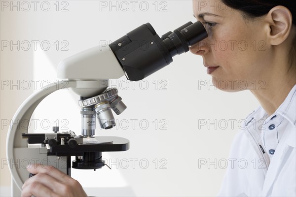 Female scientist looking into microscope.