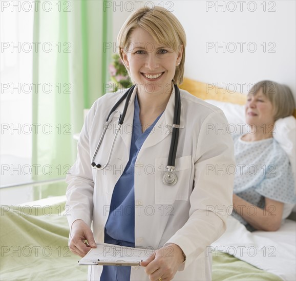 Female doctor in front of senior woman in hospital bed.